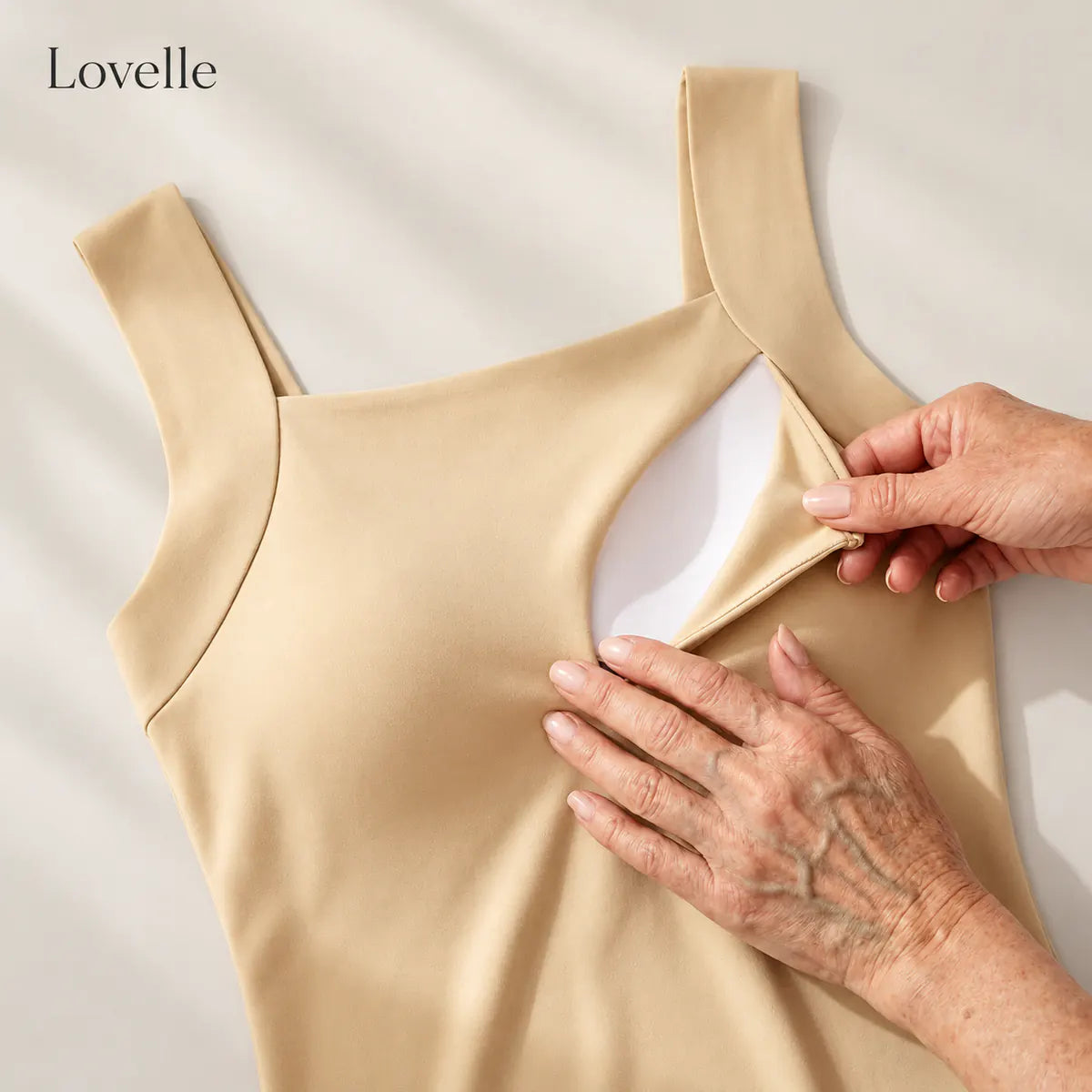 Kädet näyttävät irrotettavan pehmusteen taskun Lovelle Ease -topissa (nude)